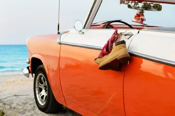 Fotobehang Vermiljoen Retro auto met gebonden laarzen en bandana aan een deurklink