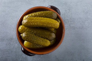Pickled gherkins with mustard and garlic on a stone rusty background.