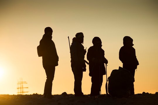 Tourists and tourist guides with rifle in backlight, silhouette, sunset, Kobbefjord, Spitsbergen archipelago, Svalbard and Jan Mayen, Norway, Europe