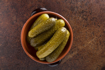Pickled gherkins with mustard and garlic on a stone rusty background.