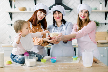 Portrait of three generations of women baking cupcakes in the kitchen, little baby girl playing with dough. Happy family together love harmony christmas cooking and mother’s day concept