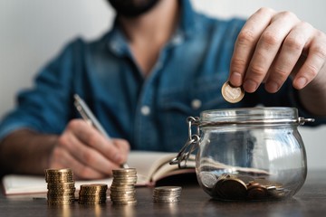 business accounting with saving money with hand putting coins in jug glass concept financial.