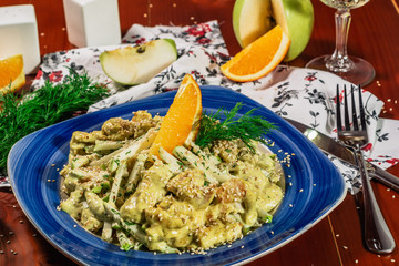 Fresh salad with chicken, orange, apple and green curry sauce. Served with white wine and cheese on the blue plate. Wooden background. horizontal view