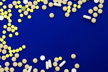 Assorted pharmaceutical medicine pills, tablets and capsules on blue background. Creative idea. Drugs. Sad. Die. Illness.