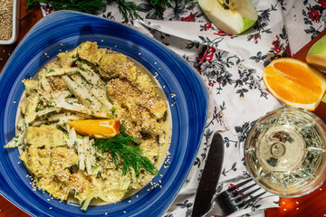 Chicken salad with apple and orange pieces, green curry sauce and sesam seads. Served with white wine and cheeser. Wooden background. Top view