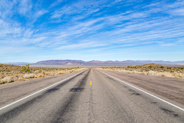 Fototapeta na wymiar A long road through a remote Nevada landscape, with a blue sky overhead