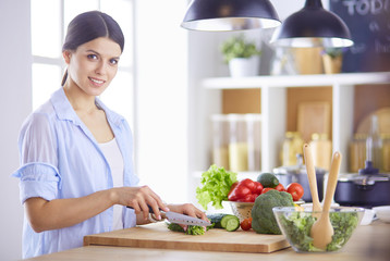 Young woman cutting vegetables in kitchen at home.