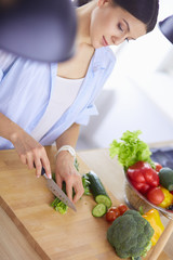Young woman cutting vegetables in kitchen at home.