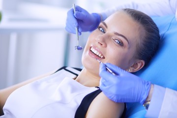 Fototapeta premium Young Female patient with open mouth examining dental inspection at dentist office.
