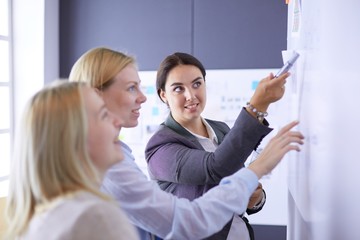 Business, education and office concept - business team with flip board in office discussing...