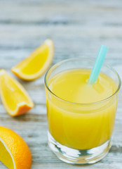 A glass of fresh orange juice and orange fruits on a wooden table. vertical view close-up. refreshing citrus drink.