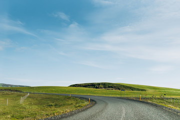 Fototapeta na wymiar Asphalt road between green grass. The road is on the background of a blue sky. Asphalt road in Iceland.