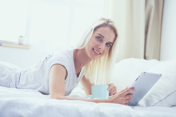 Obraz na płótnie Canvas Girl holding digital tablet with blank screen and smiling at camera in bedroom