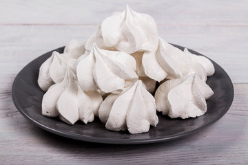 Fototapeta na wymiar merengues on gray plate on white wooden background