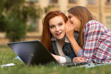 College girls using laptop together on campus