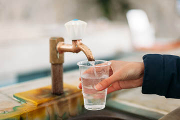 Yessentuki, Stavropol Territory / Russia - February 26, 2019: Drinking gallery of mineral spring Essentuki № 4. indoors. close - up of young woman gaining glass of mineral water from tap