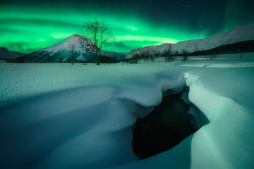 frozen river in the mountains with aurora borealis 
