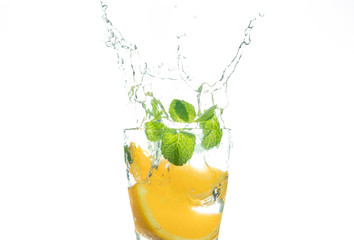 Slice the orange slice in a glass of water and make a spray on a white background. water spray in the air. a slice of citrus drops in a glass spray.