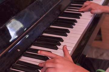 Child plays old piano with hands.