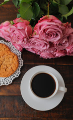 cup of coffee and roses on wooden table. Holiday concept, a bouquet of roses for a birthday,  a bouquet of flowers on his girlfriend in the morning.