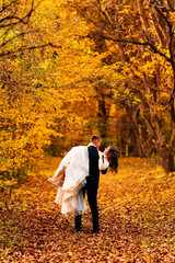 the groom holds bride in beautiful dress in his arms. they look