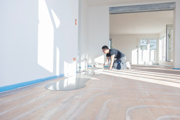 Plasterer during floor covering works with self-levelling cement mortar