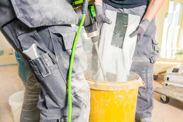 Mixing plaster solution in a bucket, using an electric drill