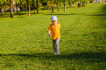 Cute boy running across grass und smiling.