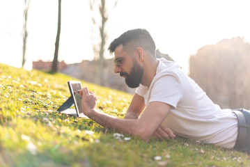 Hipster Man Using a digital Tablet in a Park.