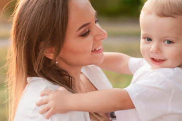 Smiling happy mother and little son playing together in the park. happy woman and child. The concept of happiness family, motherhood, love, and maternal love.