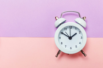 Ringing twin bell vintage classic alarm clock Isolated on purple pink pastel colourful background. Rest hours time of life good morning night wake up awake concept. Flat lay top view copy space