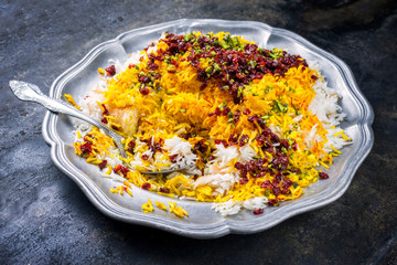 Traditional Iranian steamed saffron rice with berberis and pistachios as closeup on a pewter plate