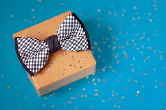 One gift box wrapped in craft paper and tied with the bow tie on blue background.