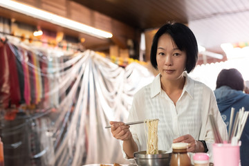 mature Asian woman eat noodles