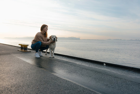 Germany, Hamburg, woman with dog on pier at the Elbe shore