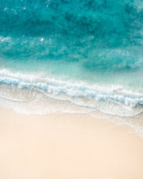 Beautiful aerial shot of a beach with nice sand, blue turquoise water. Top shot of a beach scene with a drone