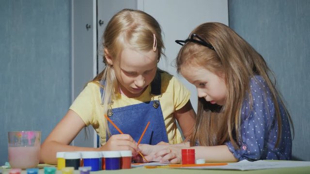 Two sisters with enthusiasm paint the coloring of watercolors