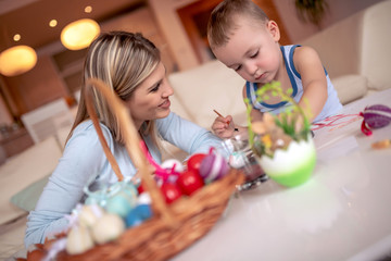 Mother and her son painting colorful Easter eggs