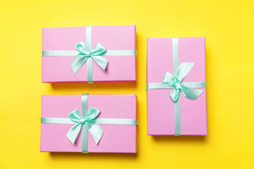 Christmas New Year birthday valentine celebration present romantic concept. Three gift boxes wrapped pink paper isolated on yellow colourful trendy modern background. Flat lay top view copy space