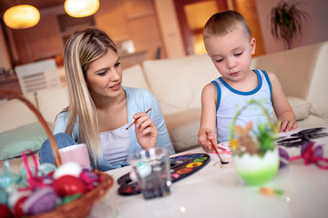 Mother and her son painting colorful Easter eggs