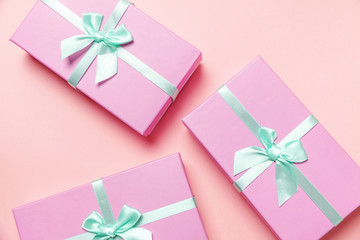 Christmas New Year birthday valentine celebration present romantic concept. Three small gift boxes wrapped pink paper isolated on pink pastel colorful trendy background. Flat lay top view copy space