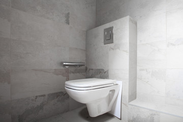Naklejka na ściany i meble New white toilet hanging set on a granite tiles wal. Unfinished Interior of repair and renovation bathroom. A bathroom remodeling project and design wetroom.