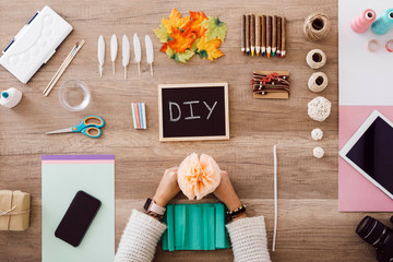 Top view of young woman doing crafts with paper flowers in her studio