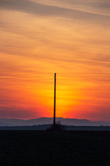 Spectacular sunset over plowed agricultural field with an electric pylon in Southern Bulgaria