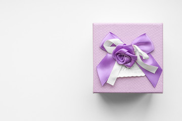Top view of purple gift box with satin ribbon bow on white background