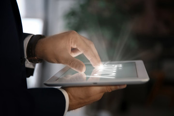 Businessman using digital tablet at workplace, closeup of hand. Mockup for design