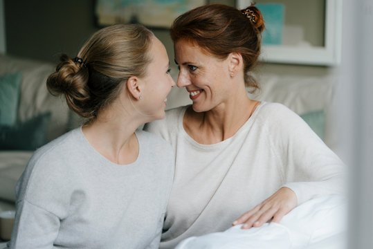 Happy mother with teenage girl face to face on couch at home