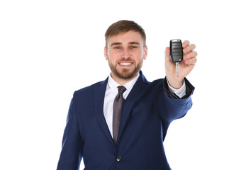 Happy young businessman with car key on white background