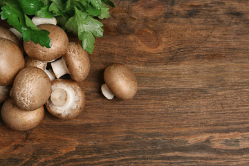 Fresh champignon mushrooms on wooden background, top view with space for text