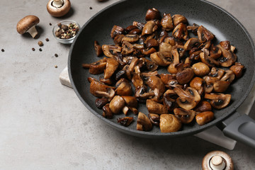 Frying pan with mushrooms on grey table